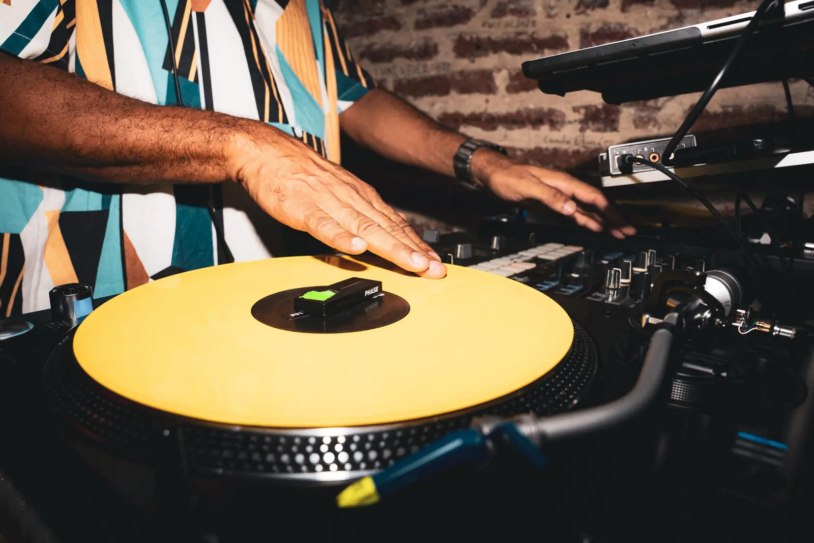 Manos sobre una tornamesa con un vinilo amarillo